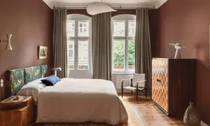 Ein Schlafzimmer in warmen, gedeckten Farben. Braune Wände, ein gemustertes Kopfteil und ein helles Bett schaffen eine gemütliche Atmosphäre.