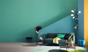 Ein Wohnzimmer mit petrolfarbener Wand, die zu einem blauen und gelben Bereich übergeht. Welche Farbe passt zu Petrol? Hier: Grün, Gold und Blau.