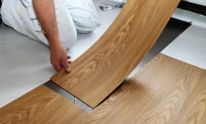 Hand verlegt Holzoptik-Vinylboden. Die Dielen werden präzise nebeneinander gelegt, um ein schönes Ergebnis zu erzielen.