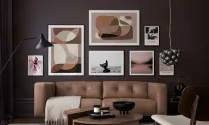 Ein braunes Ledersofa vor einer Wand mit abstrakter Kunst und einem Foto. Welche Farbe passt zu Schwarz? Hier: Braun und Beige.