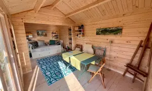 Gemütliches kleines Gartenhaus innen gestalten: Tagesbett, Esstisch und Staffelei laden zum Entspannen und Kreativsein ein.