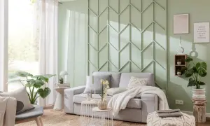Moderne Wandgestaltung im Wohnzimmer hinter der Couch mit geometrischen Mustern in Mintgrün. Gemütliche Couch mit Kissen und Decke.