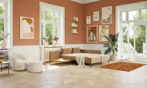 Ein gemütliches Wohnzimmer mit orangefarbenen Wänden. Ein beiger Teppich und ein Sofa, welche farbe passt zu orange, harmonieren perfekt.