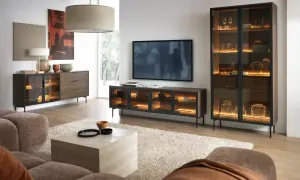 Ein stilvolles Wohnzimmer, in dem sich grau und braun harmonisch ergänzen. Ein beiger Teppich und eine braune Couch bilden die Basis, während dunkle Holzmöbel mit integrierter Beleuchtung Akzente setzen.