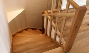 Holztreppe mit geschwungenen Treppenstufen. Der Handlauf und die Stufen sind aus hellem Holz gefertigt, was den Eindruck von Wärme und Natürlichkeit vermittelt. Die Treppenstufen streichen ist hier nicht nötig, da das Holz bereits schön zur Geltung kommt.