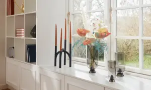 Dekorative Kerzen und Blumen auf der Fensterbank schaffen eine gemütliche Atmosphäre.