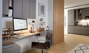 Moderne homeoffice ideen: Ein aufgeräumter Schreibtisch mit iMac, Lederstuhl und Regalwand. Daneben eine Holzwand, die in eine Küche übergeht.