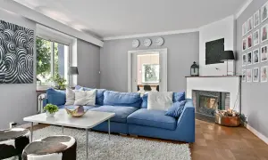 Blau und Weiß passen wunderbar zu Grau. Ein gemütliches Wohnzimmer mit blauem Sofa, weißem Teppich und Kunst an der Wand.