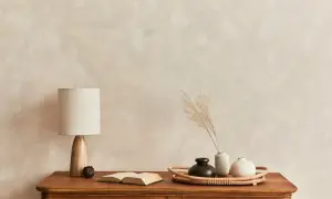 Eine Kommode mit Lampe, Buch und Vasen vor einer Wand mit **limewash technik**.
