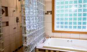Badezimmer mit Dusche und Badewanne, umgeben von Glasbausteinen. Die Glasbausteine verlegen schafft ein helles und modernes Ambiente.