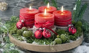 Ein **ausgefallener Adventskranz** mit vier roten Kerzen, geschmückt mit Moos, Tannenzweigen und kleinen Kugeln mit den Zahlen 1, 2, 4.