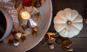 Gemütliche Herbstdeko-Ideen: Kerze, Kürbis, Eicheln und Kastanien auf einem Tablett.