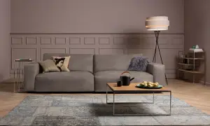 Ein taupefarbenes Sofa mit Kissen und ein Couchtisch mit Obstschale. Welche Farbe passt zu Taupe? Hier sehen Sie eine elegante Kombination mit Blau und Grau.