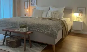 Gemütliches Schlafzimmer in Beige: Bett mit Steppdecke, Kissen und Holzbank. Tolle schlafzimmer beige ideen für eine entspannte Atmosphäre.