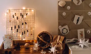 DIY Adventskalender Ideen: Ein Drahtgitter mit nummerierten Zetteln und Lichterkette, daneben braune Briefumschläge mit Weihnachtsmotiven.