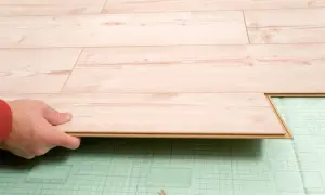 Hand verlegt helles Laminat auf grüner Trittschalldämmung. Ein neues Bodenprojekt beginnt.