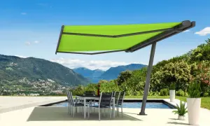 Moderne sonnensegel befestigen ideen: ein ausfahrbares Sonnensegel schützt eine Terrasse mit Esstisch und Stühlen vor der Sonne, mit Bergpanorama.
