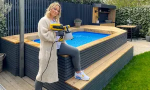Frau mit Sprühgerät verkleidet aufstellpool mit Holz.