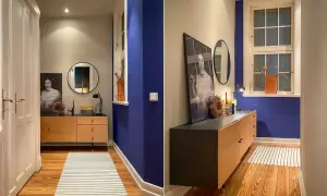 Flur mit Wand in tiefem Indigo, Holzmöbel, Spiegel und Kunstwerk. Ein Streifenmuster auf dem Teppich ergänzt die Szene.