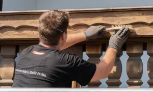 Mann bürstet Holzpaneele für das Streichen.