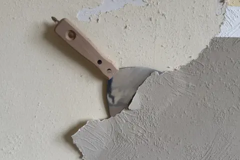 Spachtel schält Tapete ab. Die Arbeit, Tapete entfernen, ist im Gange.