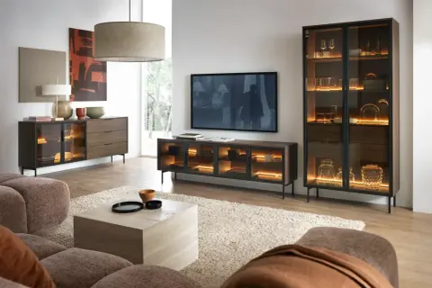 Ein stilvolles Wohnzimmer, in dem sich grau und braun harmonisch ergänzen. Ein beiger Teppich und eine braune Couch bilden die Basis, während dunkle Holzmöbel mit integrierter Beleuchtung Akzente setzen.