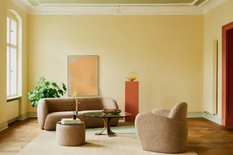 Ein Wohnzimmer mit gelben Wänden und einer grünen Decke. Die **Decke und Wand gleiche Farbe** ist hier nicht gegeben, aber die Farben harmonieren.
