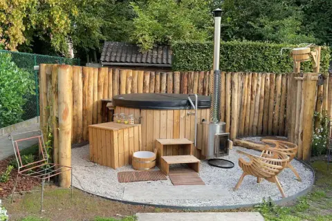 Natürliche Whirlpool Garten Ideen: Ein Holz-Whirlpool mit Holzverkleidung und Ofen, umgeben von rustikalen Holzstämmen.
