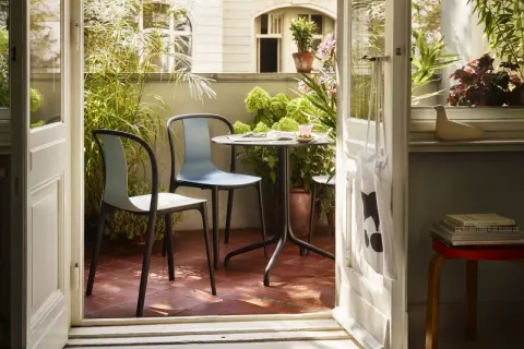 Gemütliche Balkon Ideen: Ein Tisch mit zwei Stühlen lädt zum Verweilen ein, umgeben von üppigem Grün.