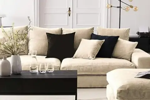 Ein helles Wohnzimmer mit einem beigen Sofa, schwarzen Akzenten und Dekorationen. Hier siehst du, was sind neutrale farben: Beige, Schwarz und Weiß dominieren.
