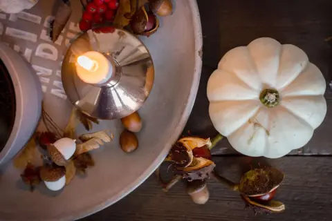 Gemütliche Herbstdeko-Ideen: Kerze, Kürbis, Eicheln und Kastanien auf einem Tablett.