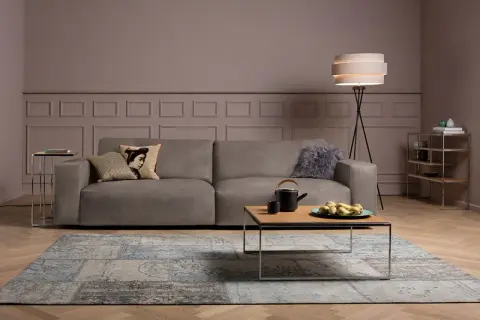 Ein taupefarbenes Sofa mit Kissen und ein Couchtisch mit Obstschale. Welche Farbe passt zu Taupe? Hier sehen Sie eine elegante Kombination mit Blau und Grau.
