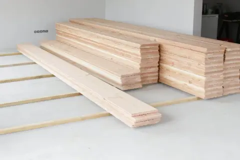 Holzdielen liegen bereit, um den **Boden auszugleichen**. Mehrere Stapel warten auf ihren Einsatz.