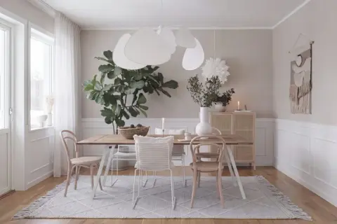 Helles, skandinavisches wohn esszimmer mit Holztisch, Stühlen, großer Zimmerpflanze und einem Rattan-Schrank.