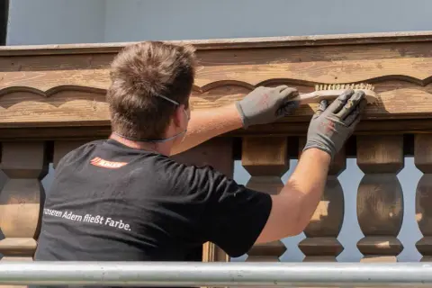 Mann bürstet Holzpaneele für das Streichen.