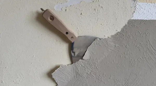 Spachtel schält Tapete ab. Die Arbeit, Tapete entfernen, ist im Gange.