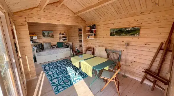 Gemütliches kleines Gartenhaus innen gestalten: Tagesbett, Esstisch und Staffelei laden zum Entspannen und Kreativsein ein.