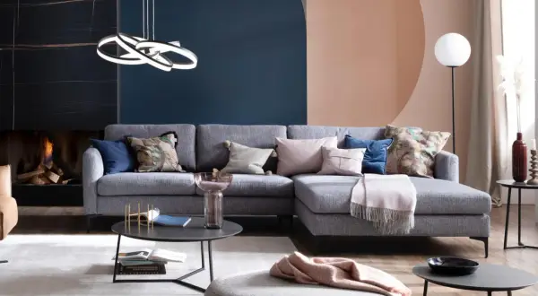 Stilvolle Ideen für ein graues Sofa: Kissen in Rosa, Blau und mit Blattmuster, eine Decke und ein Beistelltisch schaffen Gemütlichkeit.