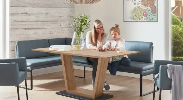Gemütliches kleines Esszimmer einrichten mit Eckbank und Holztisch. Mutter und Kind spielen am Tisch.