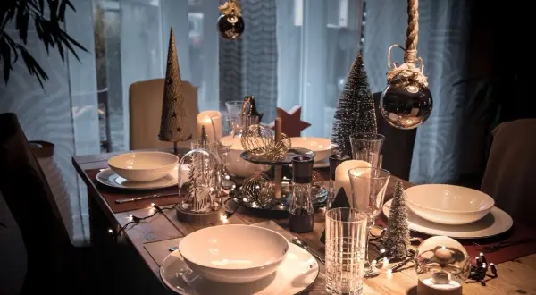 Festliche weihnachtstisch dekoration mit Kerzen, Tannenbäumen und Lichterketten.