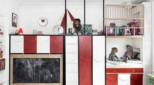 Kreative geschwisterzimmer ideen: Kinder spielen in einem bunten Zimmer mit Hochbetten, Rutsche und Tafel.