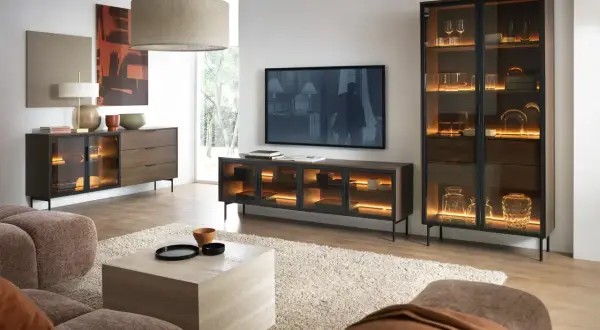 Ein stilvolles Wohnzimmer, in dem sich grau und braun harmonisch ergänzen. Ein beiger Teppich und eine braune Couch bilden die Basis, während dunkle Holzmöbel mit integrierter Beleuchtung Akzente setzen.