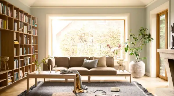 Gemütliche Anordnung Sofa Wohnzimmer mit Bücherregal, Kamin und großem Fenster.