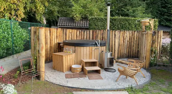Natürliche Whirlpool Garten Ideen: Ein Holz-Whirlpool mit Holzverkleidung und Ofen, umgeben von rustikalen Holzstämmen.
