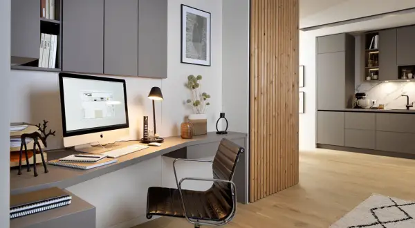 Moderne homeoffice ideen: Ein aufgeräumter Schreibtisch mit iMac, Lederstuhl und Regalwand. Daneben eine Holzwand, die in eine Küche übergeht.