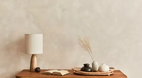 Eine Kommode mit Lampe, Buch und Vasen vor einer Wand mit **limewash technik**.