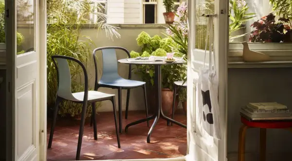 Gemütliche Balkon Ideen: Ein Tisch mit zwei Stühlen lädt zum Verweilen ein, umgeben von üppigem Grün.