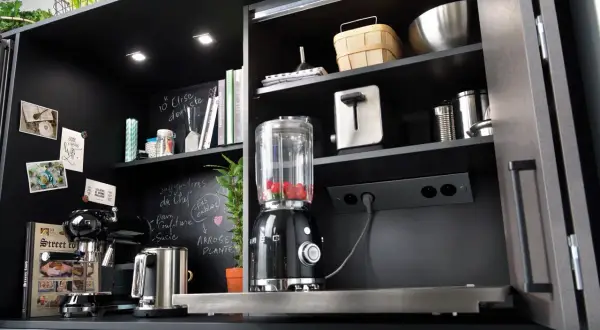 Schwarzer Küchenschrank mit integrierter Steckdose, Mixer, Kaffeemaschine und Toaster.