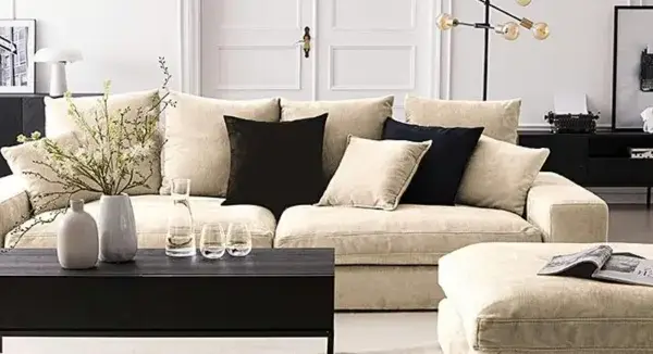Ein helles Wohnzimmer mit einem beigen Sofa, schwarzen Akzenten und Dekorationen. Hier siehst du, was sind neutrale farben: Beige, Schwarz und Weiß dominieren.