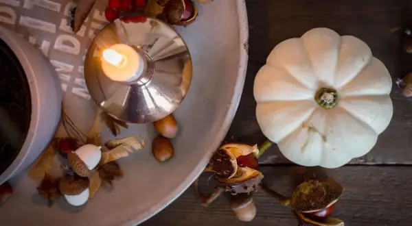 Gemütliche Herbstdeko-Ideen: Kerze, Kürbis, Eicheln und Kastanien auf einem Tablett.
